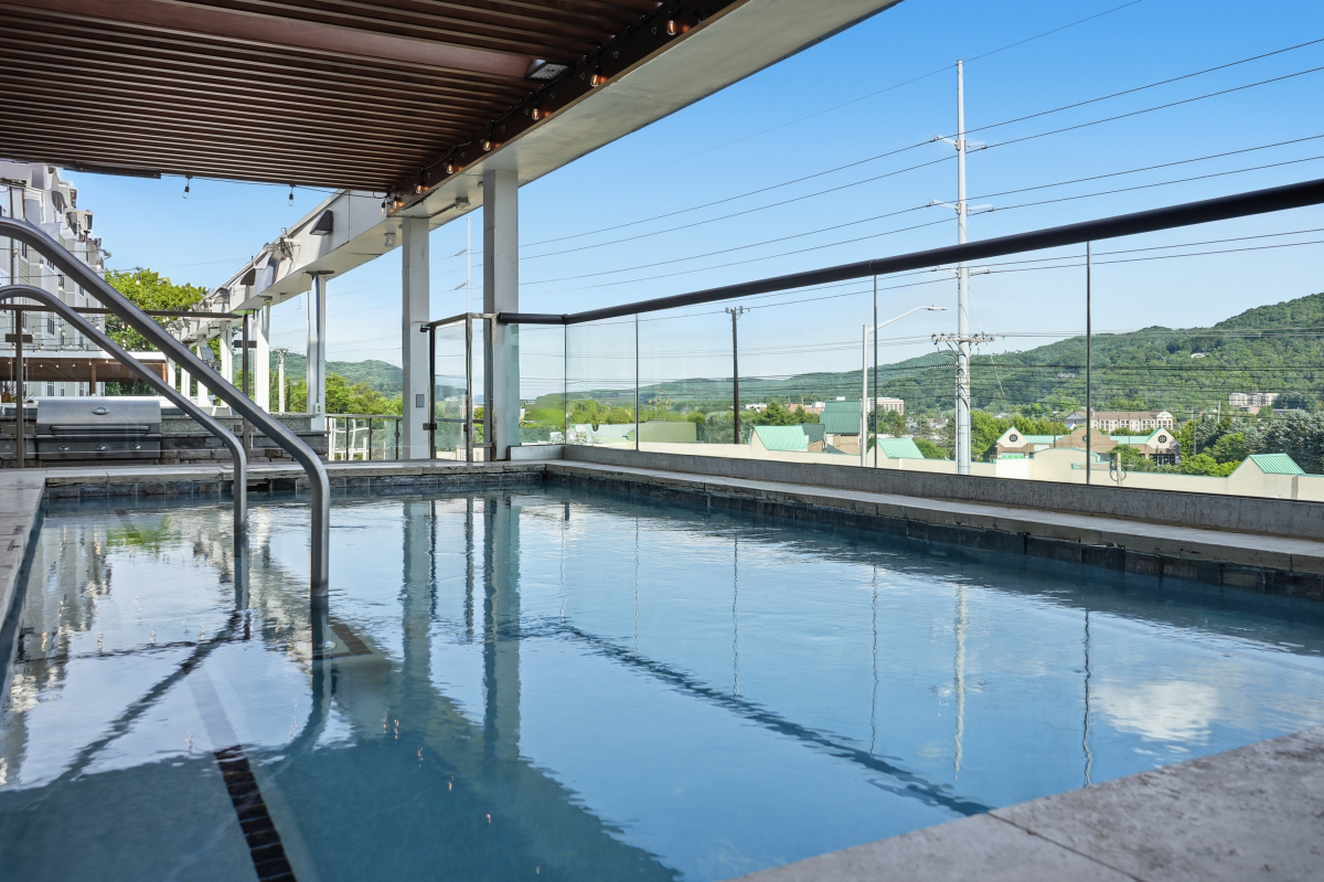 Rooftop hot tub with glass railing, covered lounge area, and scenic mountain views.