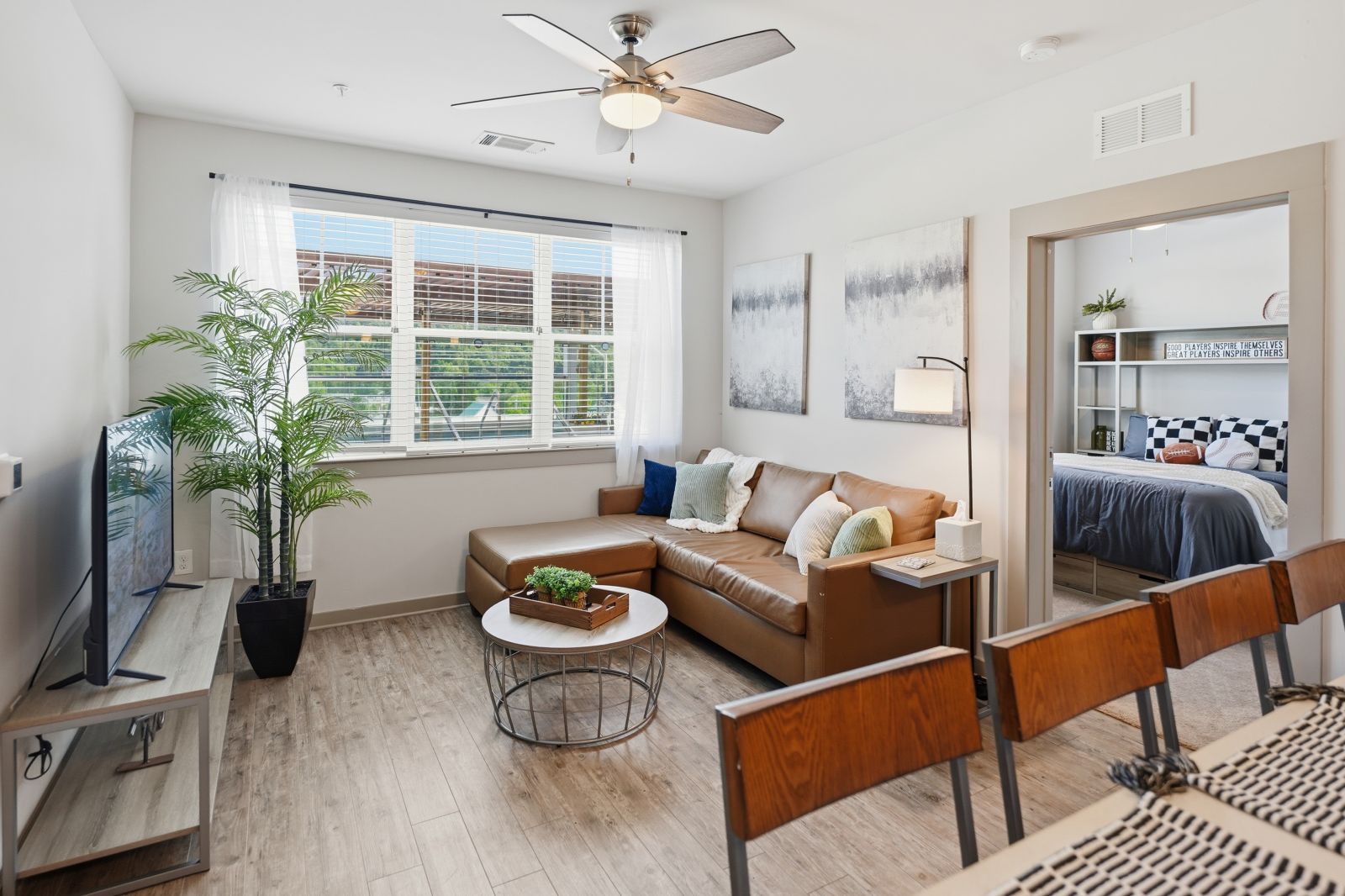 Open-concept apartment living room and kitchen with modern furnishings, stainless steel appliances, and natural light.