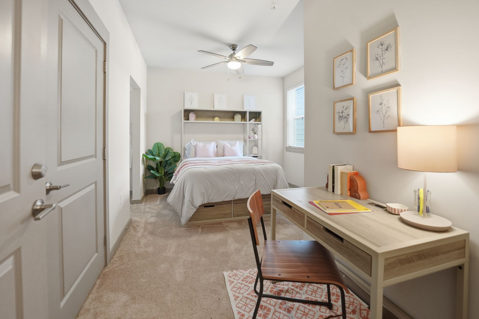 Fully furnished model bedroom featuring a study desk, plush carpeting, and modern d&eacute;cor.