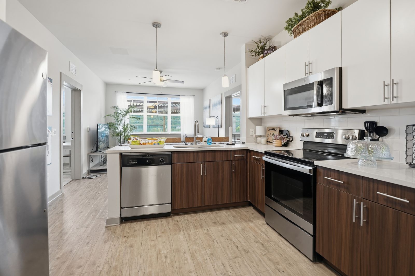 Modern apartment kitchen with stainless steel appliances, quartz countertops, and wood-style cabinetry.