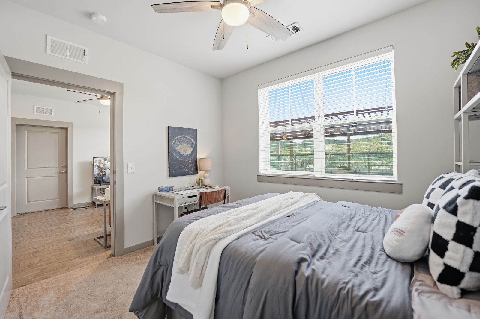 Fully furnished model bedroom featuring a study desk, plush carpeting, and modern décor.